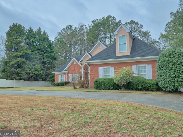 view of front of home featuring brick siding, a front lawn, and fence