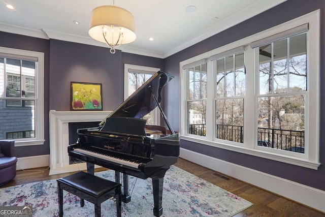 living area with crown molding, wood finished floors, and baseboards