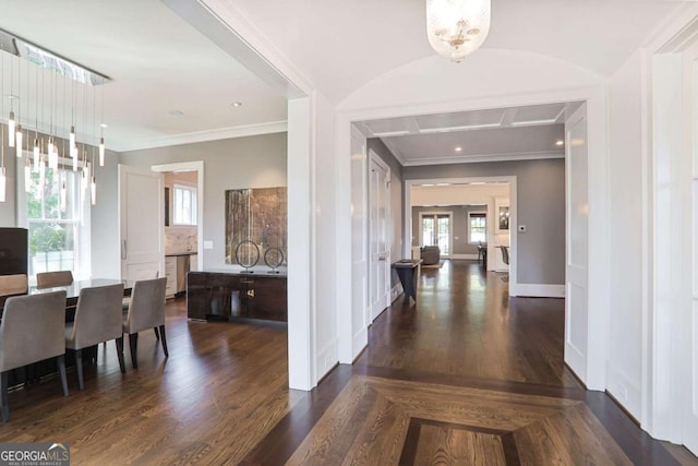 interior space with dark wood finished floors, a notable chandelier, crown molding, and baseboards