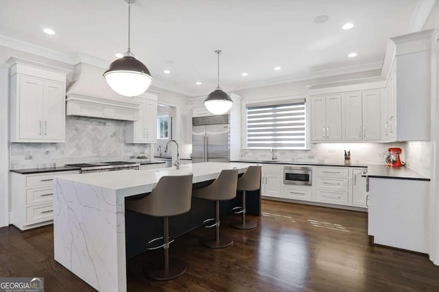 kitchen featuring custom exhaust hood, plenty of natural light, stainless steel appliances, and a kitchen island with sink