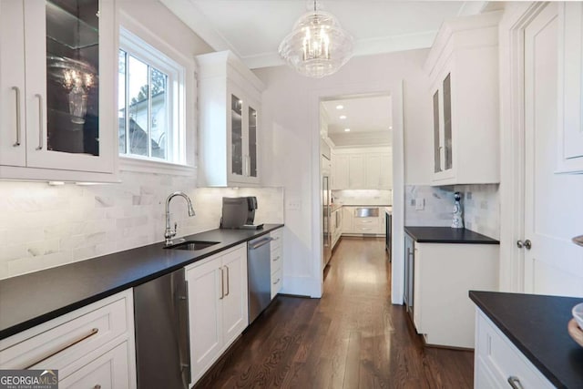 kitchen with a sink, dark countertops, stainless steel dishwasher, fridge, and white cabinets