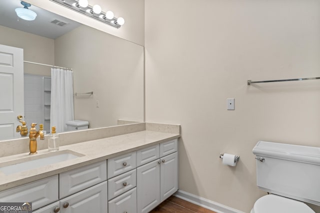 full bathroom with vanity, toilet, wood finished floors, and baseboards