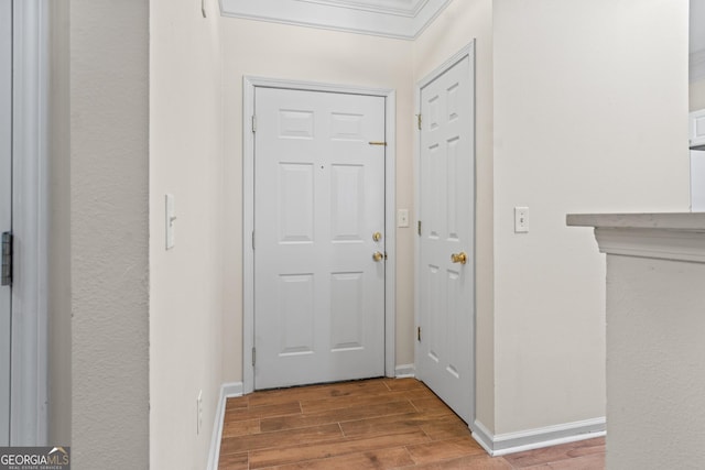 entryway with crown molding, wood finished floors, and baseboards