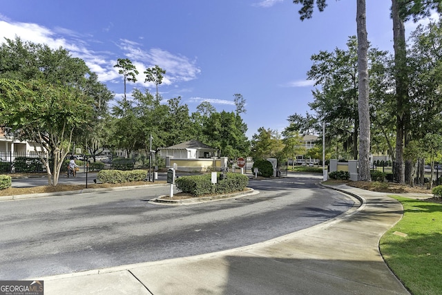 view of street with curbs, sidewalks, and a gated entry