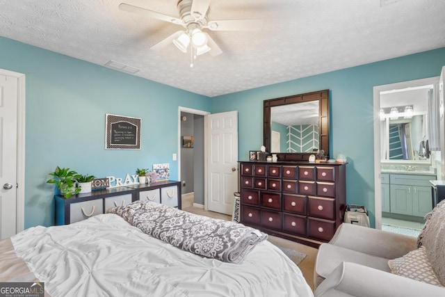 bedroom with visible vents, a textured ceiling, ensuite bathroom, and a ceiling fan