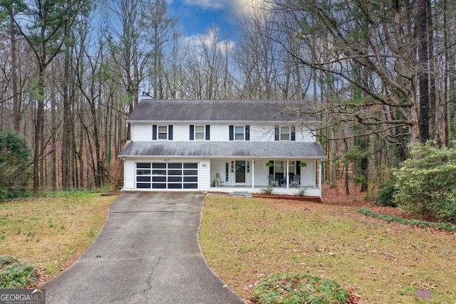 view of front of home featuring a front lawn, a porch, a chimney, a garage, and driveway