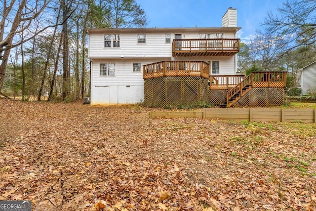 back of property featuring stairs, a wooden deck, and a chimney