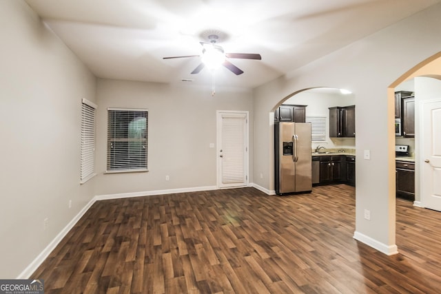 unfurnished living room featuring dark wood finished floors, a ceiling fan, and baseboards