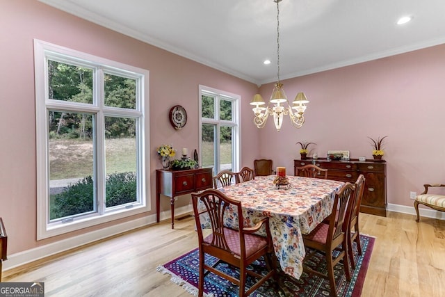 dining room with crown molding, light wood-style flooring, baseboards, and a chandelier