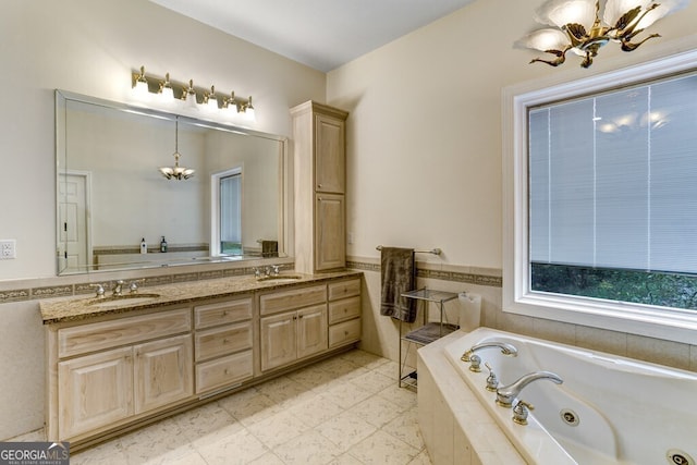 bathroom with a sink, a notable chandelier, a jetted tub, and double vanity