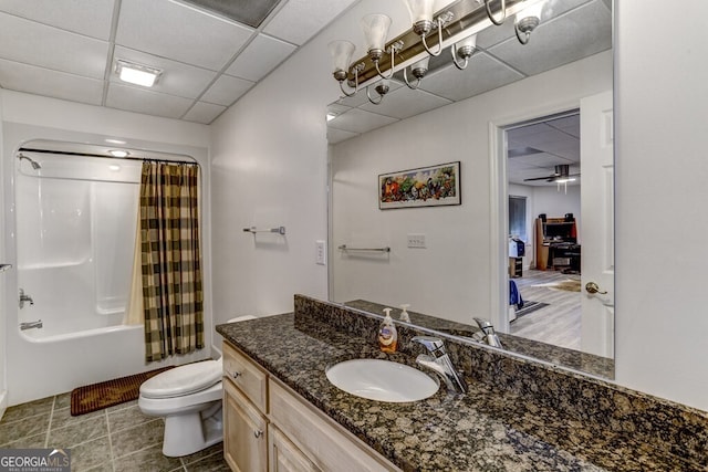 bathroom featuring tile patterned flooring, toilet, shower / tub combo with curtain, vanity, and a paneled ceiling