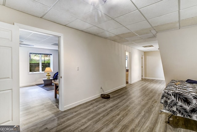 bedroom with baseboards, a paneled ceiling, and wood finished floors