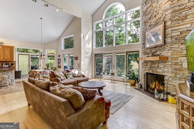 living room with a chandelier, plenty of natural light, light wood-style flooring, and a fireplace