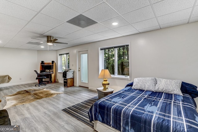 bedroom with a ceiling fan, wood finished floors, baseboards, recessed lighting, and a drop ceiling