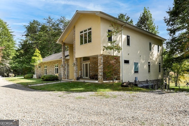 exterior space with a patio area, stone siding, and stucco siding