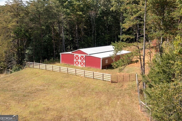 view of yard featuring an outbuilding, a forest view, and fence