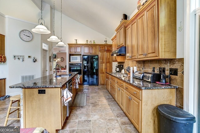 kitchen featuring a breakfast bar area, a sink, black appliances, under cabinet range hood, and backsplash