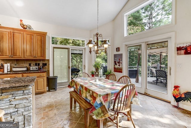 dining room with an inviting chandelier, a healthy amount of sunlight, and high vaulted ceiling