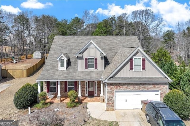 view of front of home with stone siding, driveway, and fence