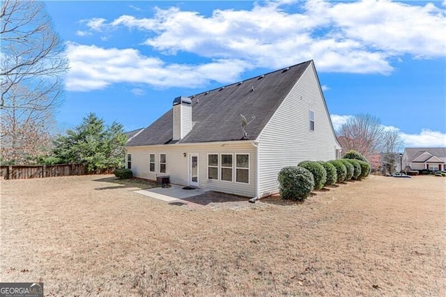 rear view of house featuring a lawn, a chimney, a patio, and fence