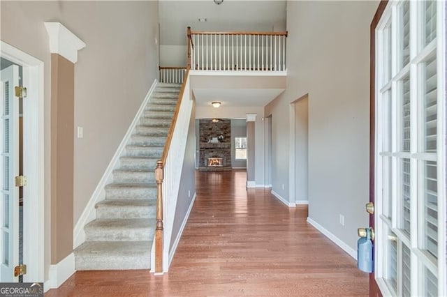 entrance foyer with stairway, wood finished floors, baseboards, and a large fireplace