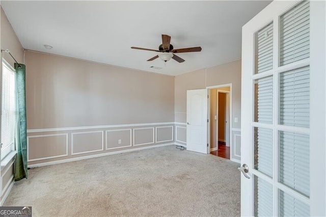 unfurnished room featuring a decorative wall, visible vents, ceiling fan, and carpet floors