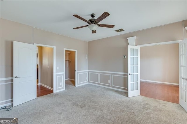 carpeted spare room with visible vents, french doors, a decorative wall, and ceiling fan