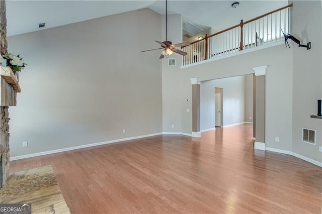 unfurnished living room featuring visible vents, high vaulted ceiling, a ceiling fan, wood finished floors, and baseboards