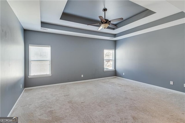 carpeted empty room featuring baseboards, a ceiling fan, and a tray ceiling