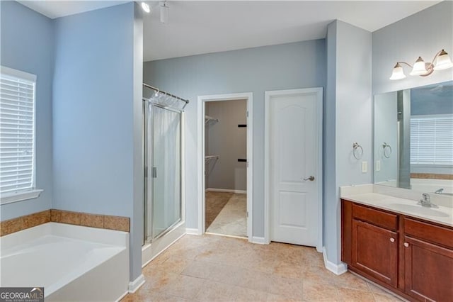 full bathroom featuring vanity, a shower stall, a walk in closet, and a garden tub