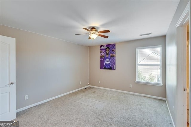 carpeted spare room featuring visible vents, baseboards, and ceiling fan