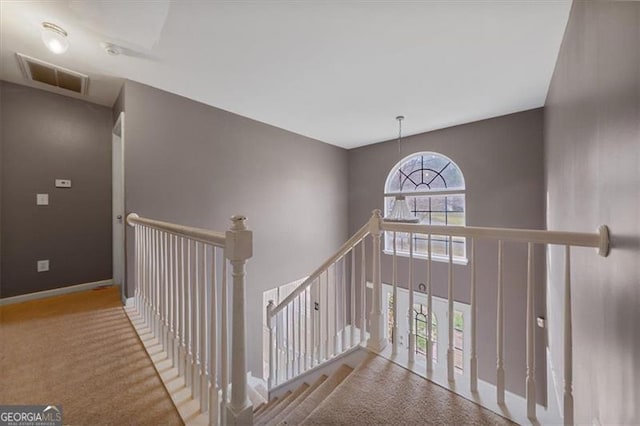 corridor featuring visible vents, an upstairs landing, carpet flooring, baseboards, and a towering ceiling