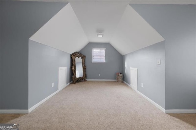 additional living space featuring baseboards, lofted ceiling, and carpet flooring