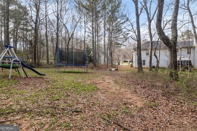 view of yard featuring a playground and a trampoline