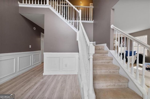 stairway featuring wood finished floors and wainscoting