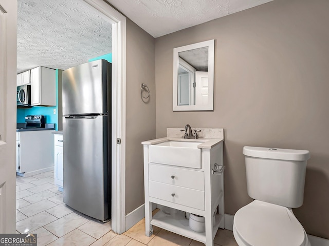 half bath with toilet, a textured ceiling, vanity, and baseboards