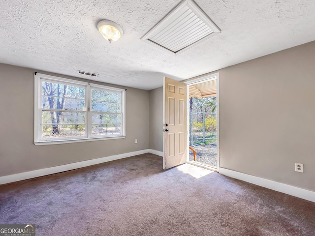 carpeted empty room featuring a textured ceiling, a healthy amount of sunlight, visible vents, and baseboards