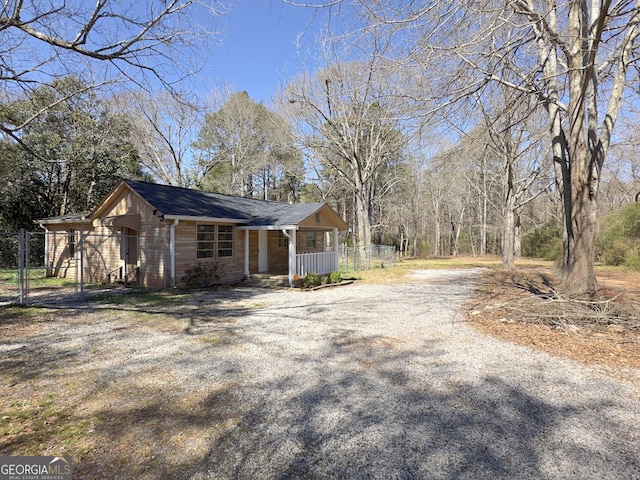 view of home's exterior featuring gravel driveway, covered porch, and fence