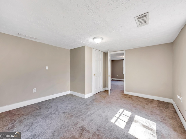 carpeted empty room with visible vents, a textured ceiling, and baseboards