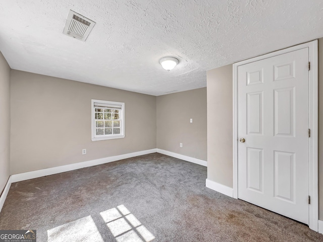 spare room featuring visible vents, baseboards, carpet, and a textured ceiling