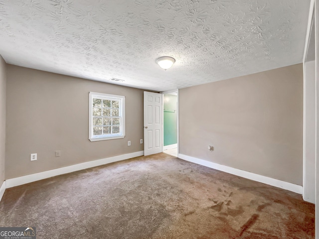 carpeted spare room with visible vents, baseboards, and a textured ceiling