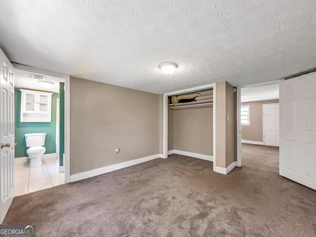 unfurnished bedroom featuring visible vents, baseboards, carpet flooring, a closet, and a textured ceiling