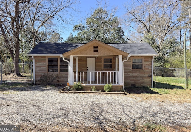 view of front of home with a porch, fence, and stone siding