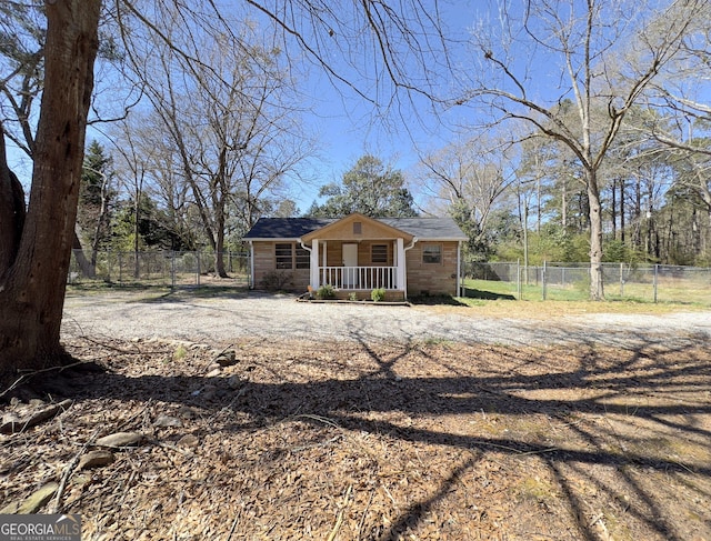 view of front of house with covered porch, fence, stone siding, and dirt driveway