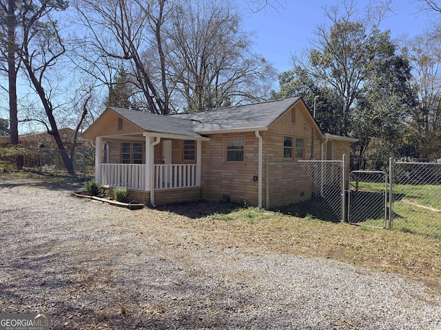 view of property exterior featuring fence, covered porch, and a gate