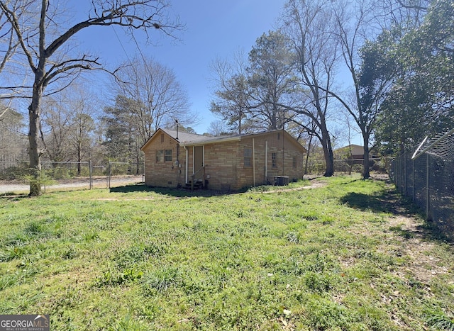 view of side of property with cooling unit, a fenced backyard, brick siding, and a lawn