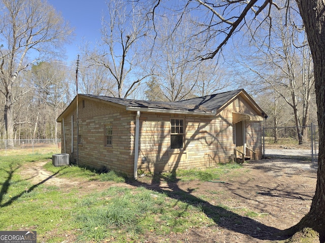 view of property exterior featuring fence, driveway, a yard, stone siding, and central air condition unit