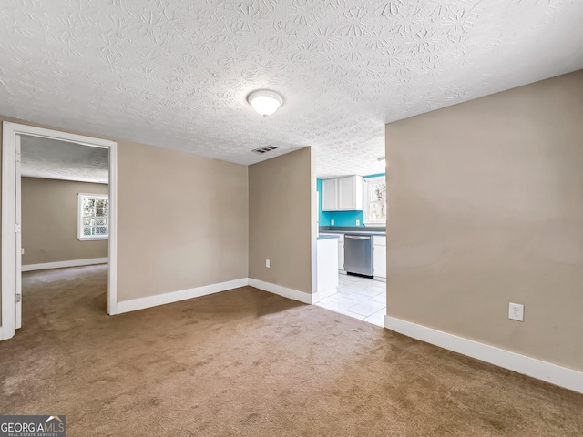 empty room with visible vents, baseboards, light colored carpet, and a textured ceiling