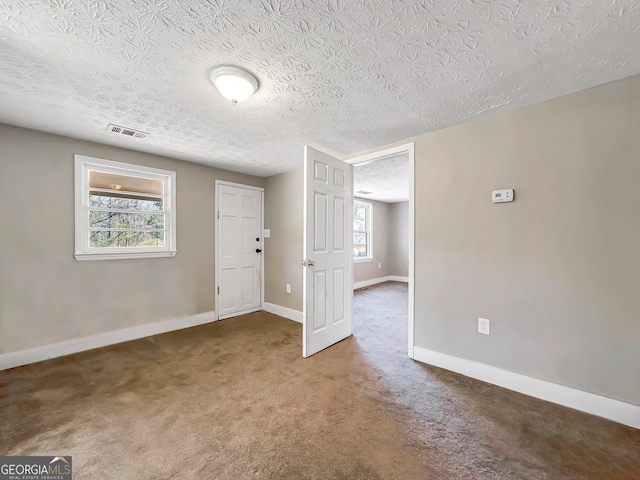 unfurnished room featuring visible vents, baseboards, carpet, and a textured ceiling