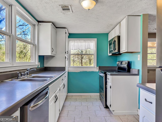 kitchen featuring visible vents, a sink, white cabinetry, stainless steel appliances, and a healthy amount of sunlight